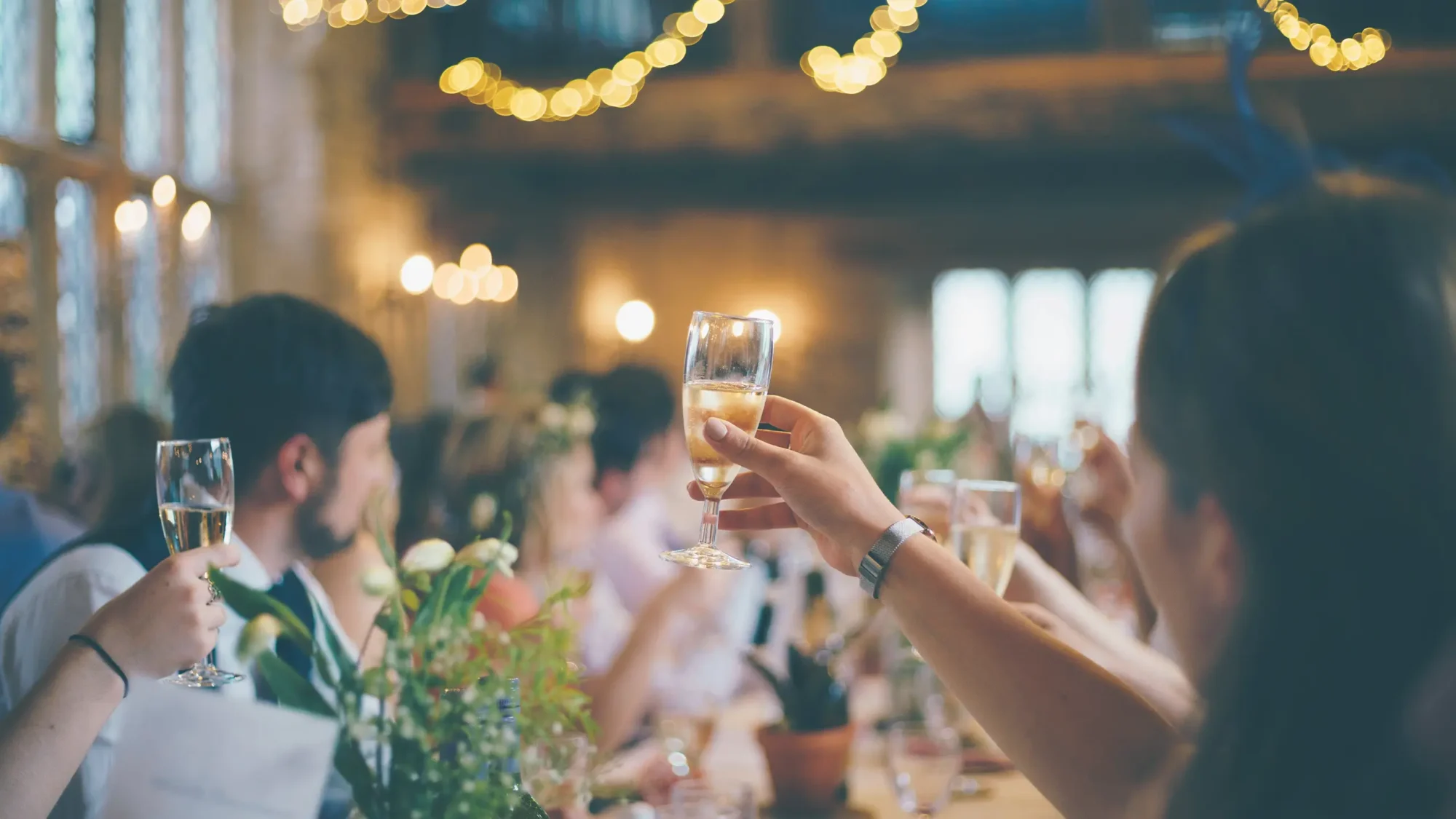 Guests raising their glasses in a toast at a wedding reception, capturing a moment of celebration and happiness