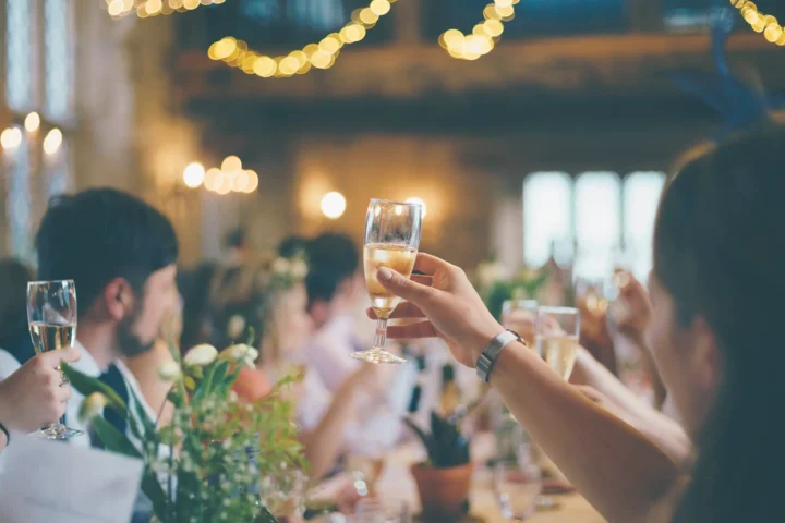 Guests raising their glasses in a toast at a wedding reception, capturing a moment of celebration and happiness