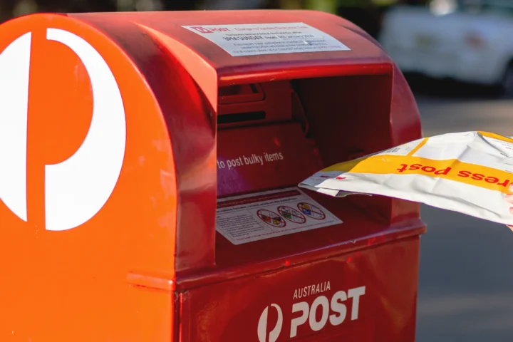 person putting their mail into a red Australia Post, post box