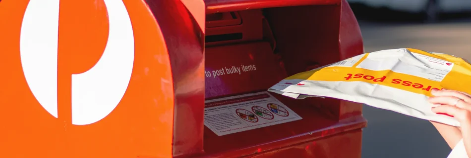 person putting their mail into a red Australia Post, post box