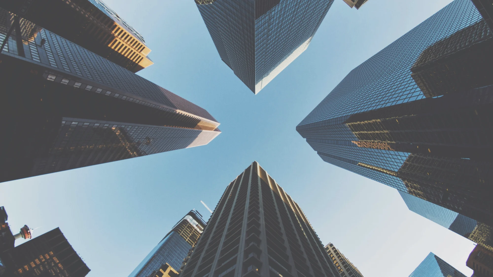 A perspective from the ground looking up at tall city buildings showing a 360 view, emphasizing their impressive height and architectural design.