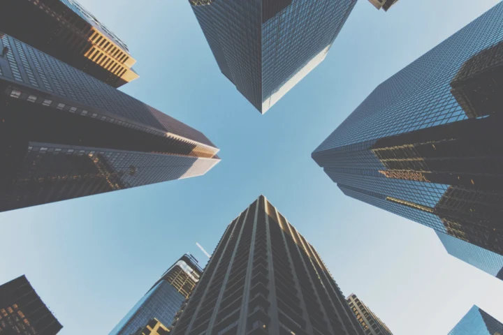 A perspective from the ground looking up at tall city buildings showing a 360 view, emphasizing their impressive height and architectural design.