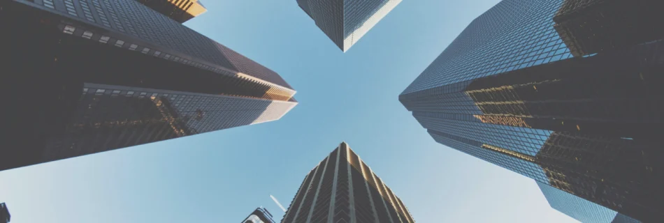 A perspective from the ground looking up at tall city buildings showing a 360 view, emphasizing their impressive height and architectural design.