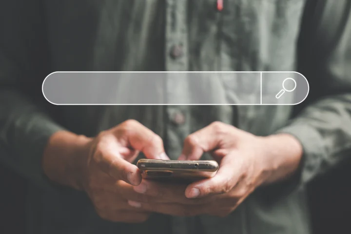 man holing a phone with a search bar govering above the phone